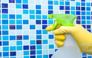 This image shows a man spraying a cleaner on the pool tiles.