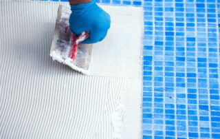 This image shows a man putting new tiles to the pool.