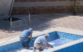 This image shows 2 men replacing the pool tiles.