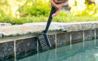 This image shows a pool tile being cleaned with a brush.